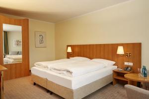 ein Schlafzimmer mit einem großen weißen Bett und einem Tisch in der Unterkunft H+ Hotel Willingen in Willingen