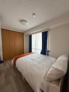 a bedroom with a large white bed and a window at 朝日街の宿 An inn on Asahi Street in Tokyo