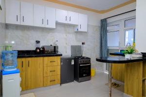 a kitchen with white cabinets and a black appliance at Happy Home Ke in Meru