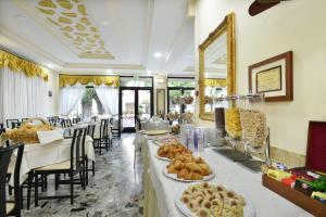 un restaurante con mesas y sillas con comida. en Hotel Ristorante Commercio, en Saló