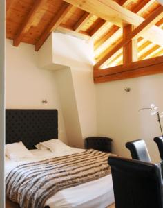 een slaapkamer met een bed in een kamer met houten plafonds bij L'Epicerie Du Monal in Sainte-Foy-Tarentaise