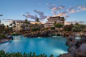 a resort pool with a waterfall and rocks at Honua Kai Konea 230 in Kahana