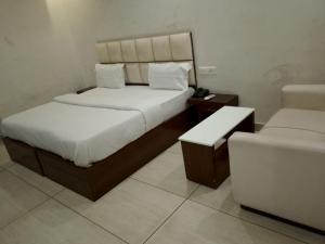 una habitación de hotel con dos camas y una silla en Hotel Prem Ratna, en Dehradun