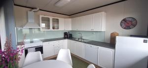 a kitchen with white cabinets and a clock on the wall at Grasbakken Panorama in Varangerbotn