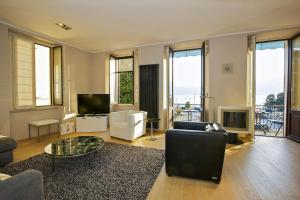 un soggiorno con divano e TV e alcune finestre di Appartamento Toscanini a Verbania