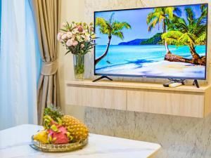 a television on a wall with a table with fruit at Lamai Beach - Apartment Leo in Nathon Bay