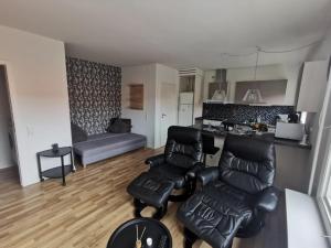 a living room with black leather furniture and a kitchen at JR Apartments in Esbjerg