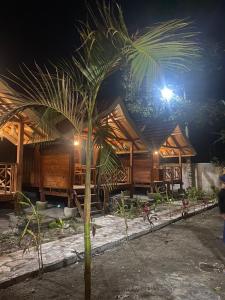 a palm tree in front of a building at night at Arsilahomestay in Tetebatu