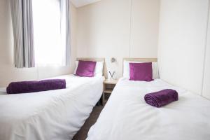 2 camas en una habitación con almohadas moradas en Pineview Retreat, en Lymington