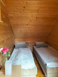 2 camas en una habitación con una mesa y un jarrón de flores en Domki Pirat, en Władysławowo