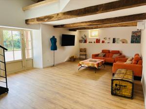 a living room with orange couches and a tv at Le Gîte Eiffel Les Gîtes de l'Atelier in Gaudonville