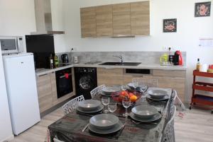 a kitchen with a table with plates and wine glasses at côté chêne in Puycornet