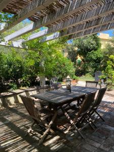 a wooden table and chairs under a pergola at Casa con Piscina a Portoferraio in San Giovanni