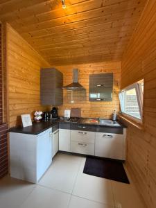 a kitchen with white cabinets and a wooden wall at domek campingowy in Brachlewo