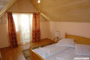 a bedroom with a bed and a window in a attic at Pension Crizantema in Vatra Moldoviţei