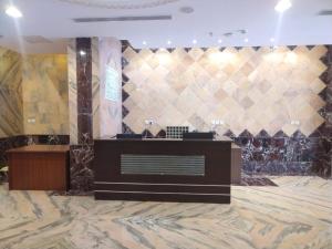 a lobby with a reception desk and a tile wall at Manazel Al Taqwa Hotel in Quai
