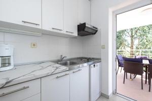 a white kitchen with a sink and a patio at Apartments Ruza in Porat