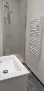 a white bathroom with a sink and a shower at apartment building features laundry facilities in Beauzelle