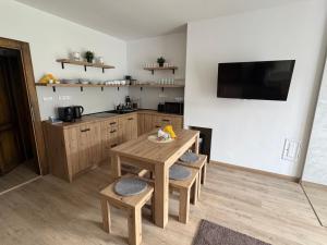 a kitchen with a wooden table and chairs and a television at Apartmán Vločka Tatranská Lomnica in Tatranská Lomnica