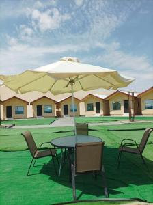 a table and chairs with a large umbrella at Qatar Traditional Bedouin Desert Camping in Ash Shaqrāʼ