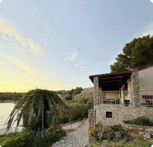 a stone house next to a body of water at House Franceskini in Sali