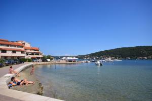 a group of people laying on a beach next to the water at Apartments Poldan in Supetarska Draga