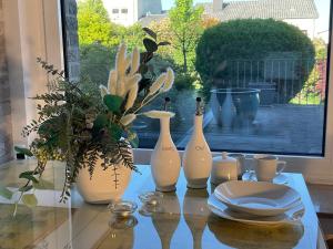 a table with three white vases and plates on it at Komfortappartement mit Terraasse in Wuppertal