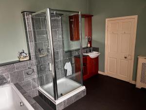 a bathroom with a shower with a tub and a sink at The Old Farmhouse in Dalkeith