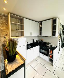 a kitchen with white cabinets and a table with a plant at Komfortappartement mit Terraasse in Wuppertal