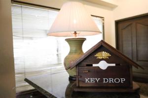 Una lámpara sobre una mesa junto a una caja de seguridad. en Phawana Sweet Hotel, en Bangkok