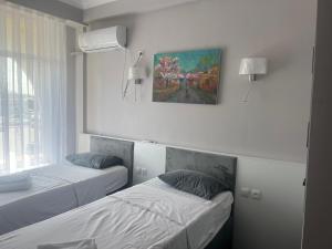 a bedroom with two beds and a painting on the wall at OSH ART Meergul in Osh
