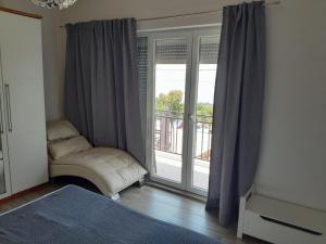 a room with a window with a chair and a balcony at Apartments Roza in Dramalj