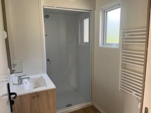 a white bathroom with a shower and a sink at Camping VVF Pontivy in Pontivy +10 photos