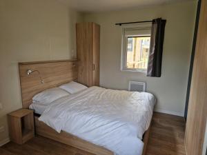 a bedroom with a white bed with a window at Camping VVF Pontivy in Pontivy
