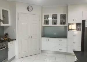 a kitchen with white cabinets and a clock on the wall at Relaxed Tropical Living in Caravonica