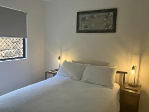 a bedroom with a white bed with two lamps and a picture on the wall at Relaxed Tropical Living in Caravonica