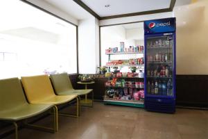 Una máquina expendedora de refrescos en un restaurante con sillas. en Phawana Sweet Hotel, en Bangkok