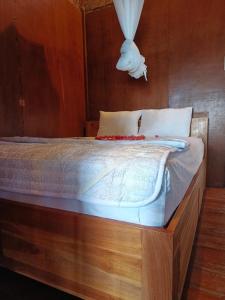 a bedroom with a wooden bed with white sheets at Lumbung House in Gili Gede
