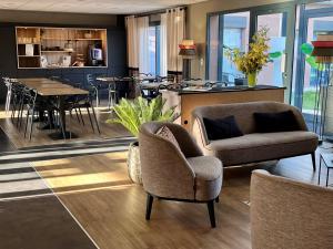 ein Wohnzimmer mit zwei Stühlen und einem Tisch in der Unterkunft Hôtel & Events LE PATIO OCCITAN Toulouse Ouest - Cugnaux in Cugnaux