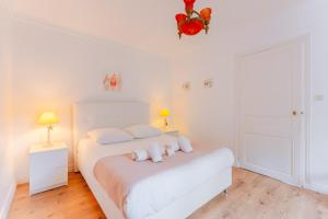 a white bedroom with a white bed and two lamps at L'Acacia - Maison pour un séjour serein à Nantes in Nantes +4 photos