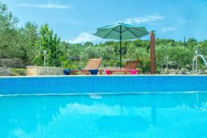 a swimming pool with two chairs and an umbrella at House Nikica in Korčula