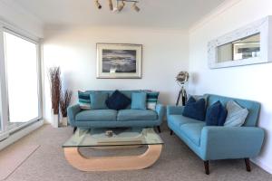 a living room with two blue couches and a coffee table at Tides - Beach front apartment in Bracklesham Bay in Chichester