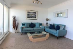 a living room with two blue couches and a table at Tides - Beach front apartment in Bracklesham Bay in Chichester