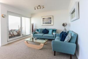 a living room with a blue couch and a table at Tides - Beach front apartment in Bracklesham Bay in Chichester