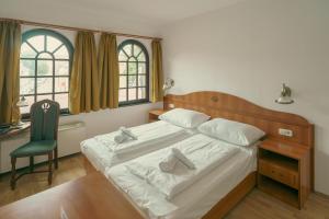 a bedroom with a bed with a desk and a chair at Révkapu Panzió Mohács in Mohács