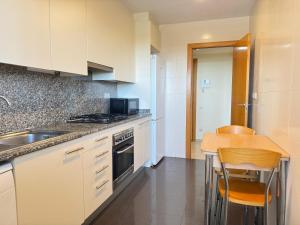 a kitchen with white cabinets and a table and a sink at Dúplex con encanto en Castelldefels in Castelldefels