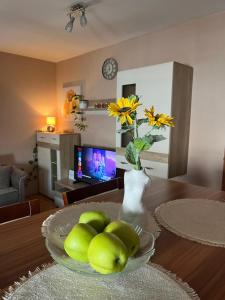a vase of green apples and a vase of flowers on a table at Lily Cozy Apartment in Niš