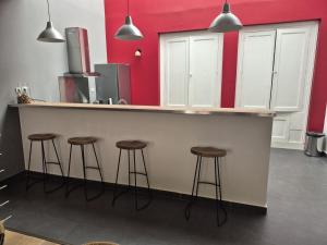 eine Küche mit einer Theke mit Hockern und roten Wänden in der Unterkunft Chic 4 personnes Hypercentre 5 Minutes Avenue De Champagne in Épernay