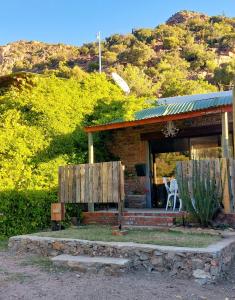 a house with a table and a chair in front of it at The Candle Cottage at Keurkloof Valley Family Farm in Uniondale