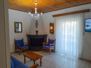 a living room with a fireplace and blue chairs at Villa Platanos in Kanali